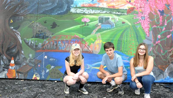 The Roost Youth Group has finished a community mural at the New Paltz Recycling and ReUse Center. The mural is their vision of what the new Carmine Liberta Bridge will look like. The official unveiling will be at a community ice cream social on August 27. Pictured left to right are: Danielle Takacs, James Hyland and Juliette Crisafi. Not pictured: Dayna Thomas and Sam Liebman. (photo by Lauren Thomas)
