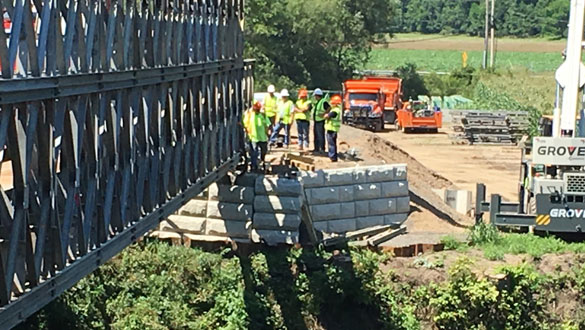 Bridge crew examines unexpected movement of temporary bridge abutment on west side of Wallkill River last week. (photo by Paul Brown)